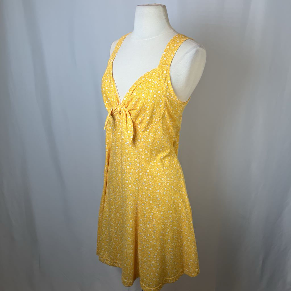 Yellow dress with a tie detail on a mannequin against a gray background