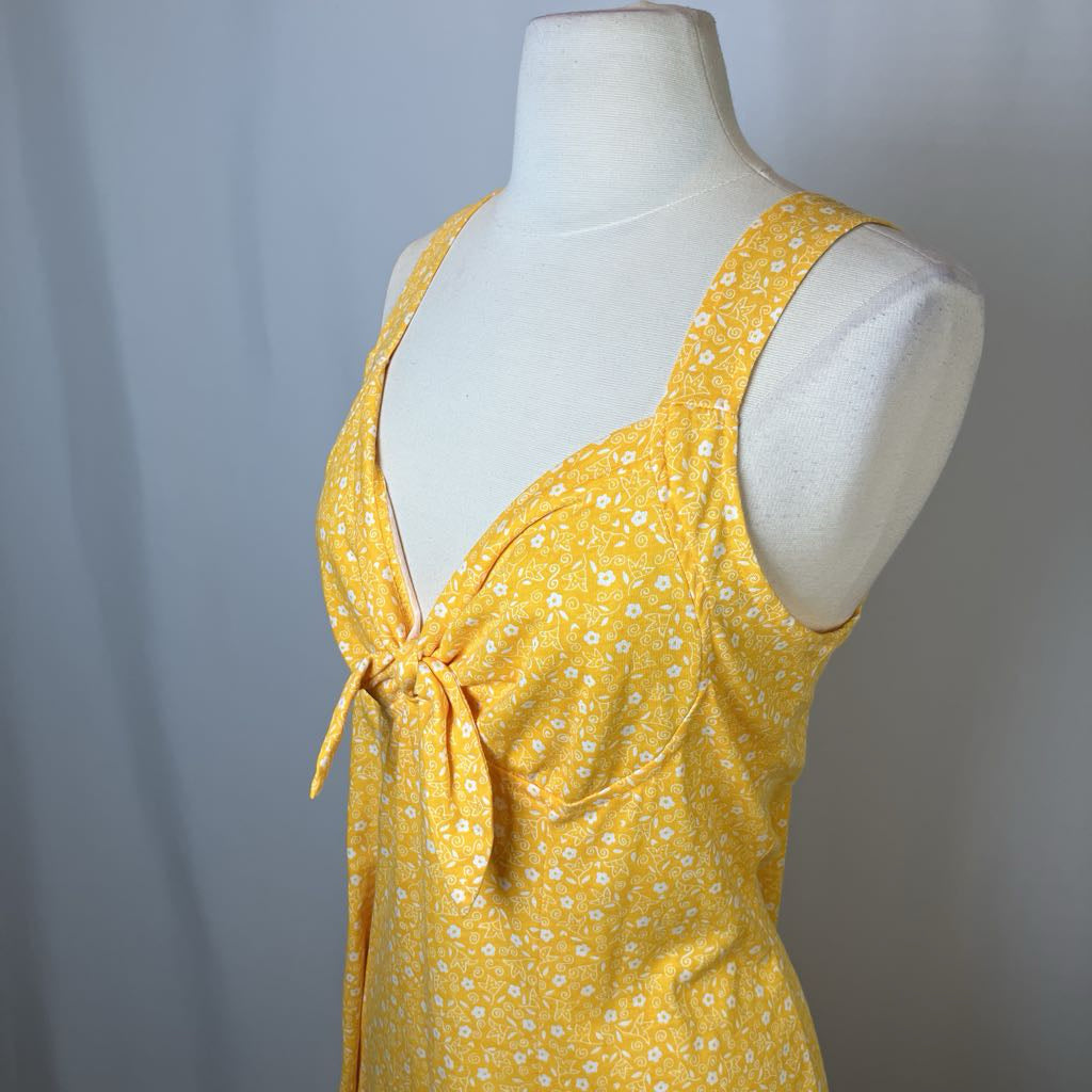 Yellow floral dress on a mannequin against a gray background