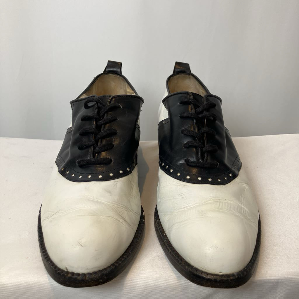 Pair of black and white shoes on a white surface with a light gray background