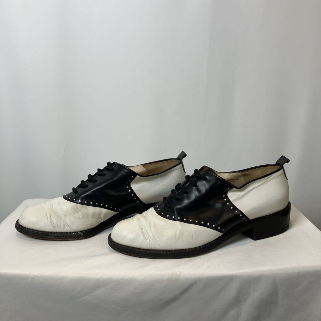 Pair of black and white shoes on a white platform with a light gray background