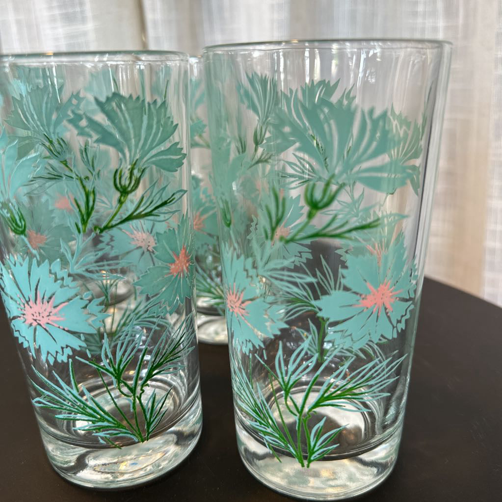 Two glass tumblers with floral design on a dark surface.