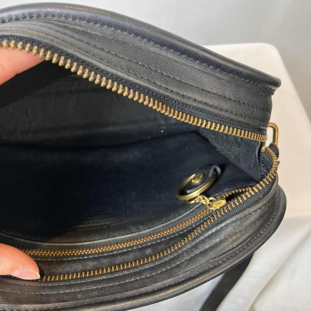 Close-up of a black leather handbag with gold zipper and stitching.