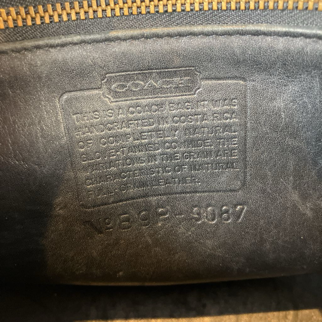 Coach leather product with brand name and model number on a dark background