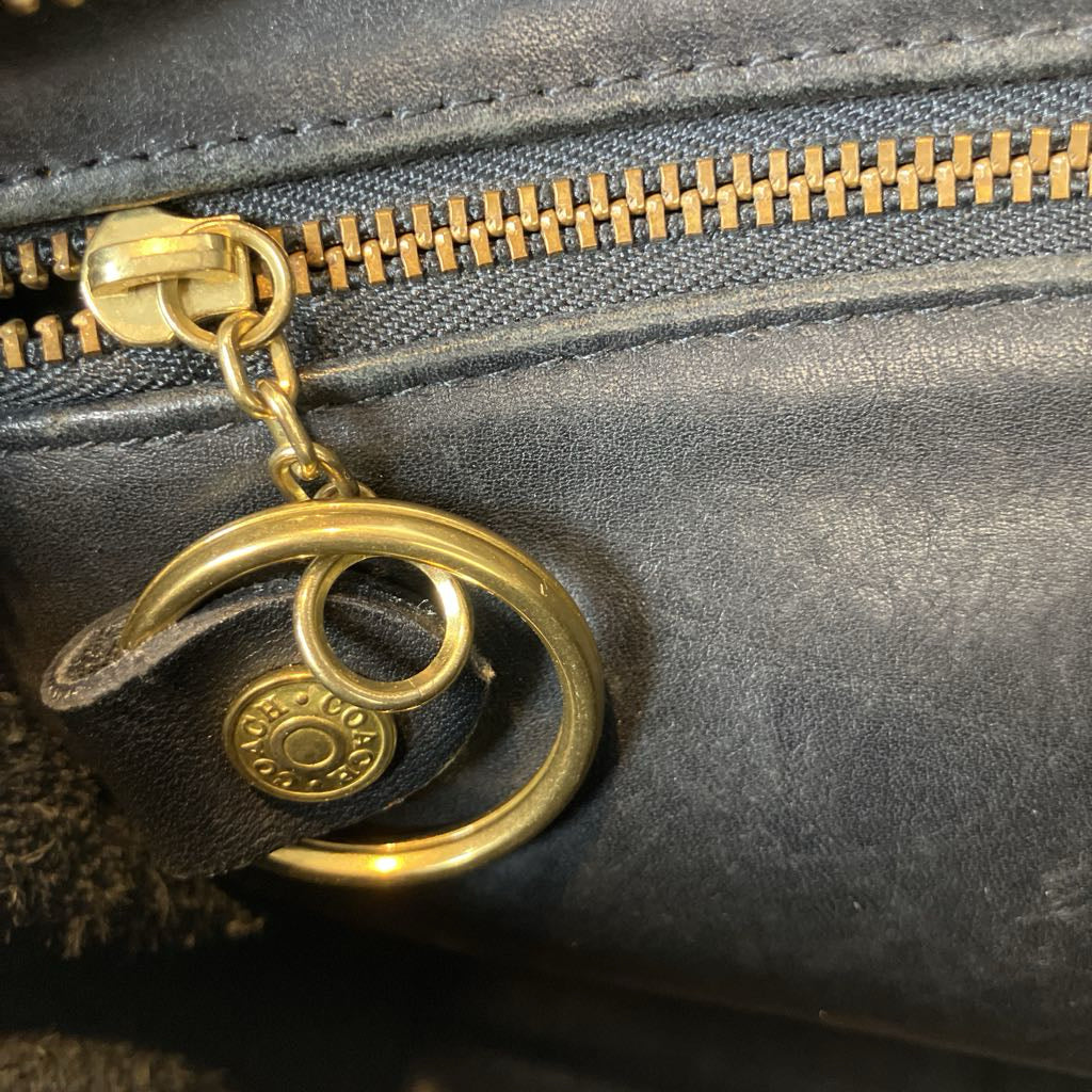 Gold zipper pull on a black leather bag