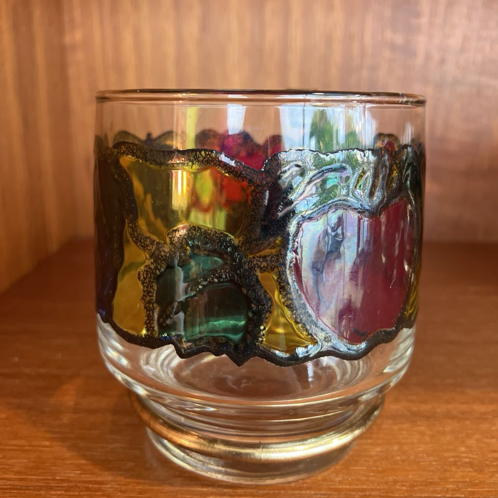 Decorative glass with colorful designs on a wooden surface