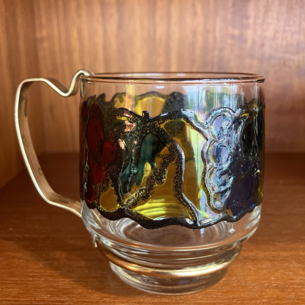 Glass mug with artistic handle design on a wooden surface