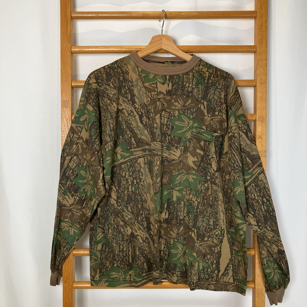Camouflage-patterned shirt on a hanger against a wooden rack.