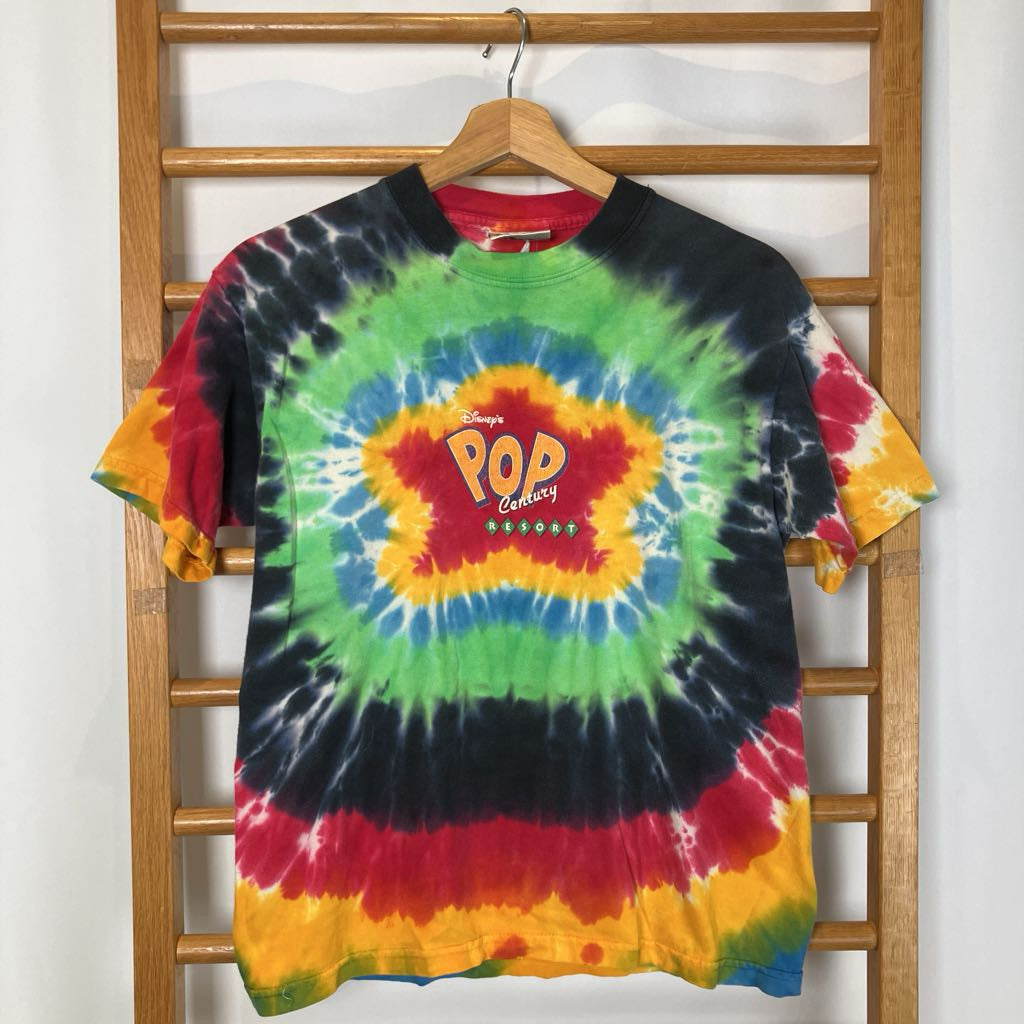 Colorful tie-dye t-shirt with 'Pop Century' logo on a wooden rack.