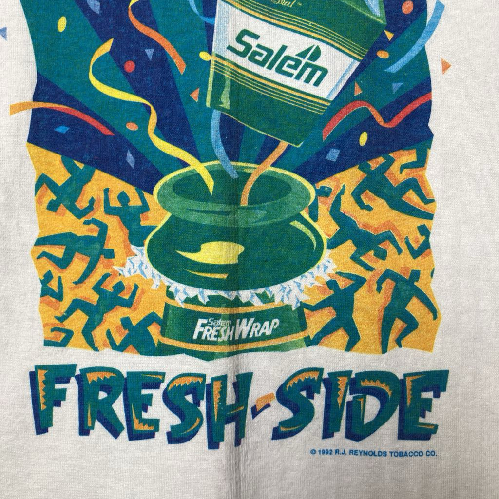 A close-up of a vintage-style graphic print on a light fabric background. The design shows a green pot with a Salem Fresh Wrap label, colorful confetti, stylized figures, and large text reading 'FRESH-SIDE' at the bottom.