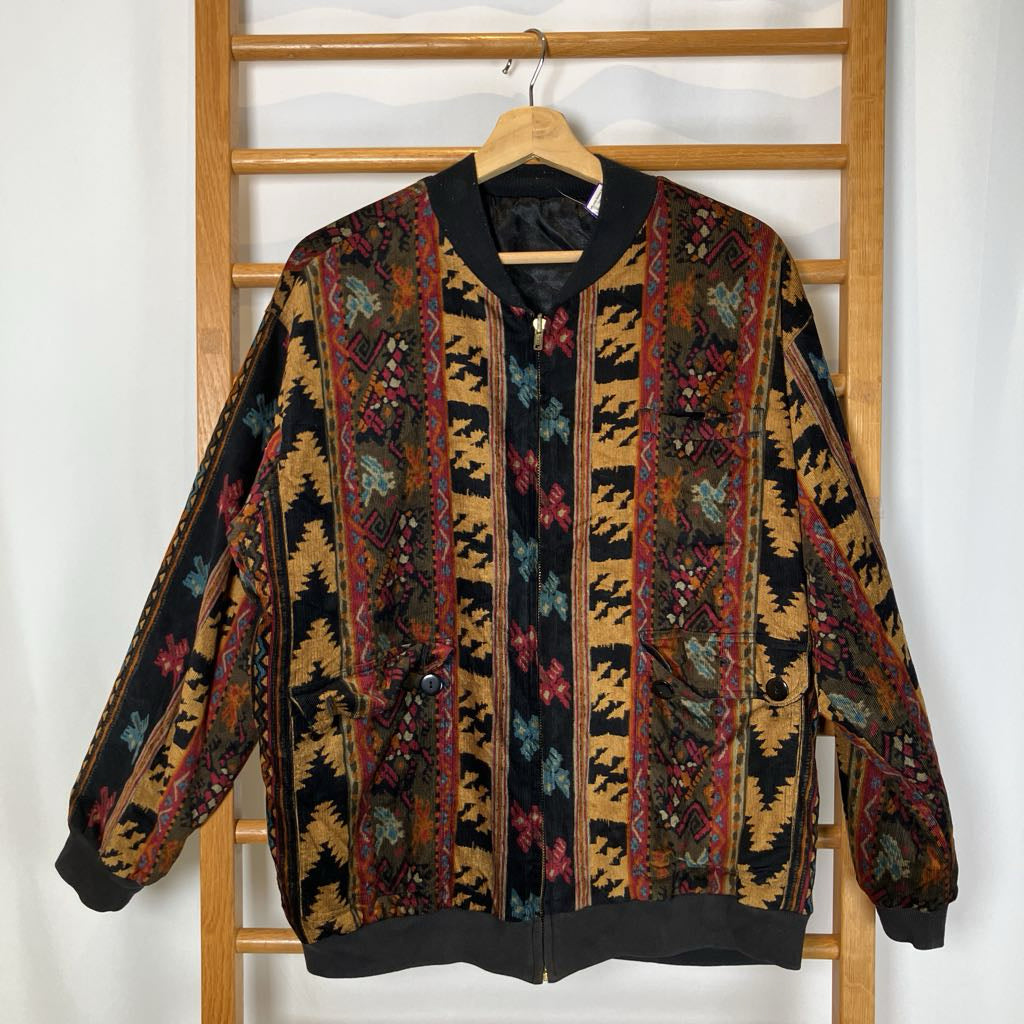 Colorful patterned jacket hanging on a wooden rack against a white wall