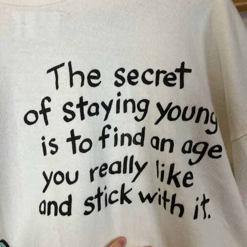 Text on a white shirt with a humorous quote about staying young.