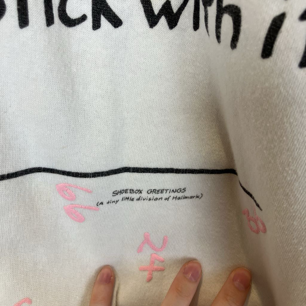Close-up of a white shoebox with text and numbers, held by a hand.
