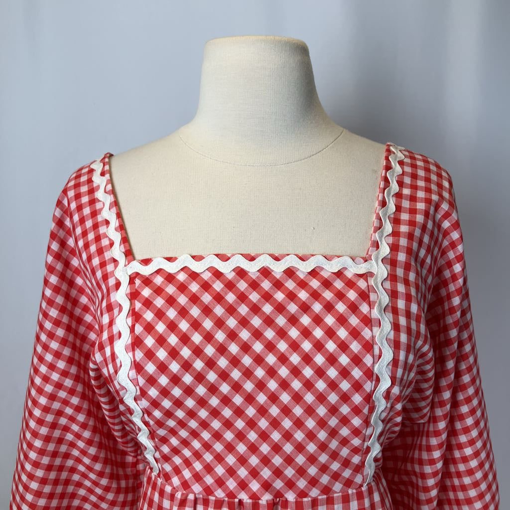 Red and white checkered dress on a mannequin against a gray background