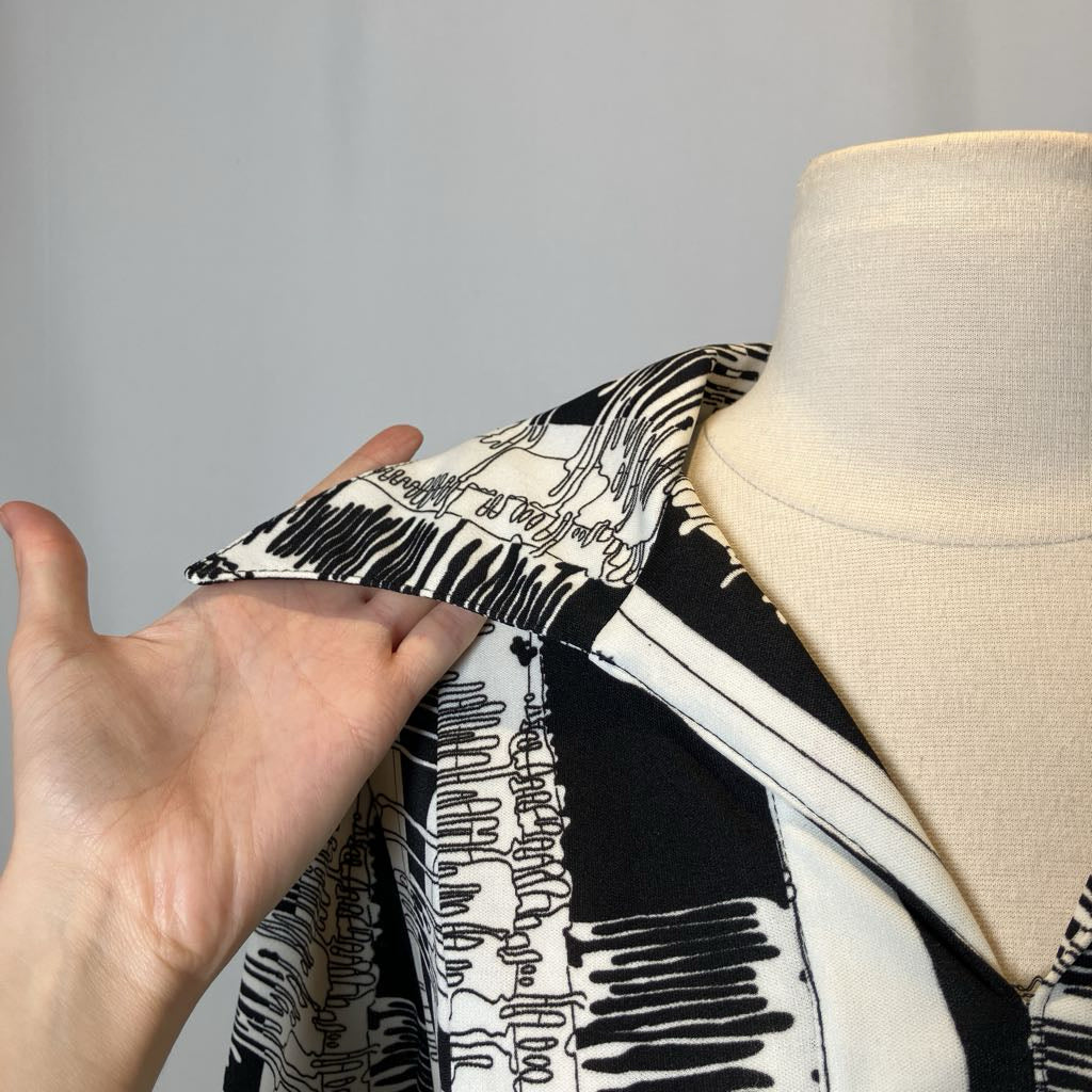 Person adjusting a black and white patterned fabric on a mannequin.