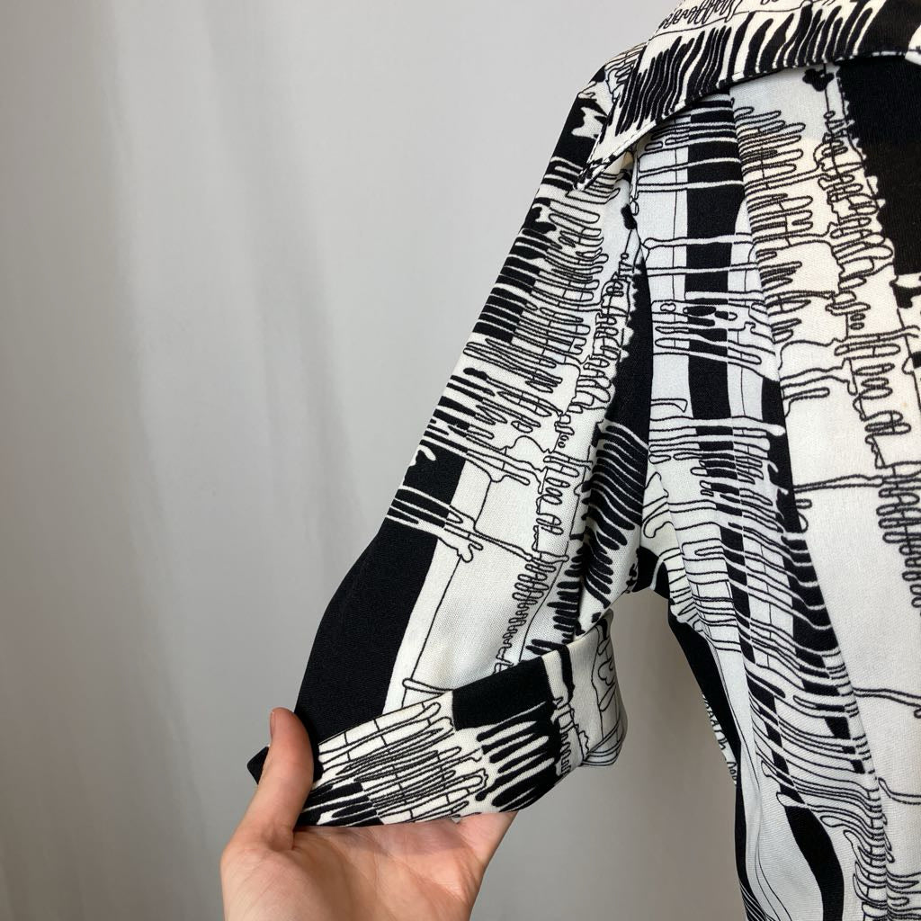 Black and white patterned fabric held by a hand against a plain background