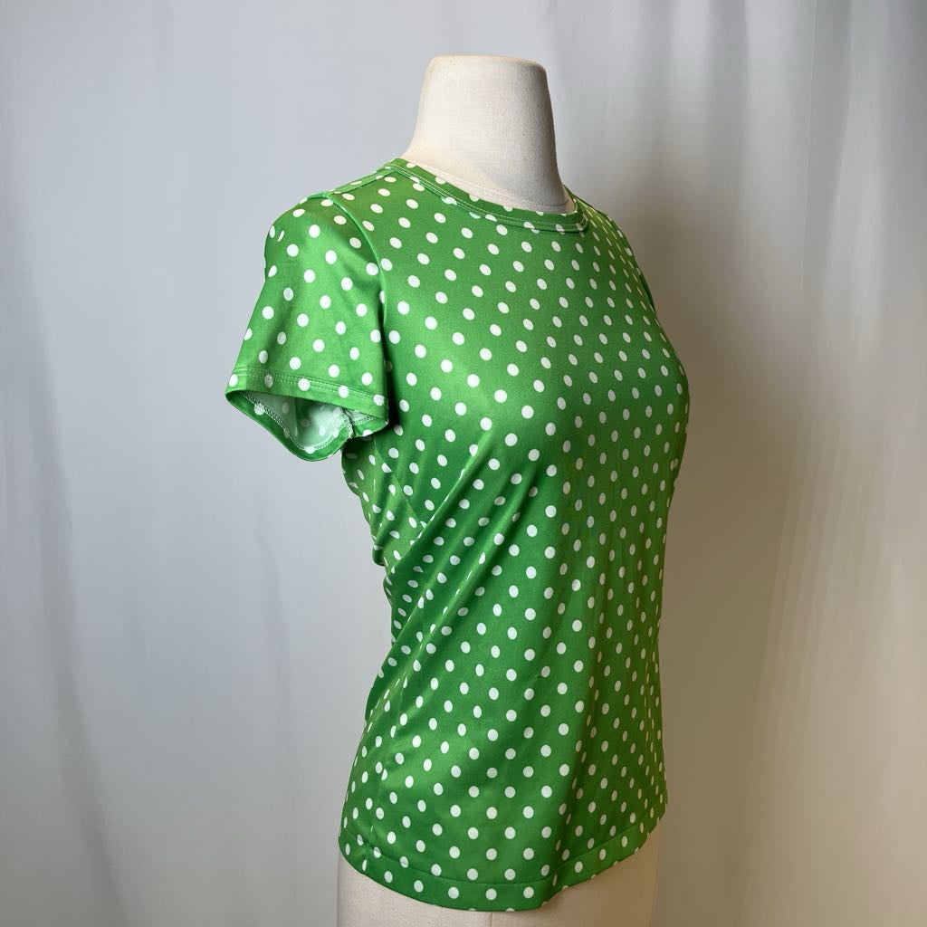 Green polka dot blouse on a mannequin against a plain background