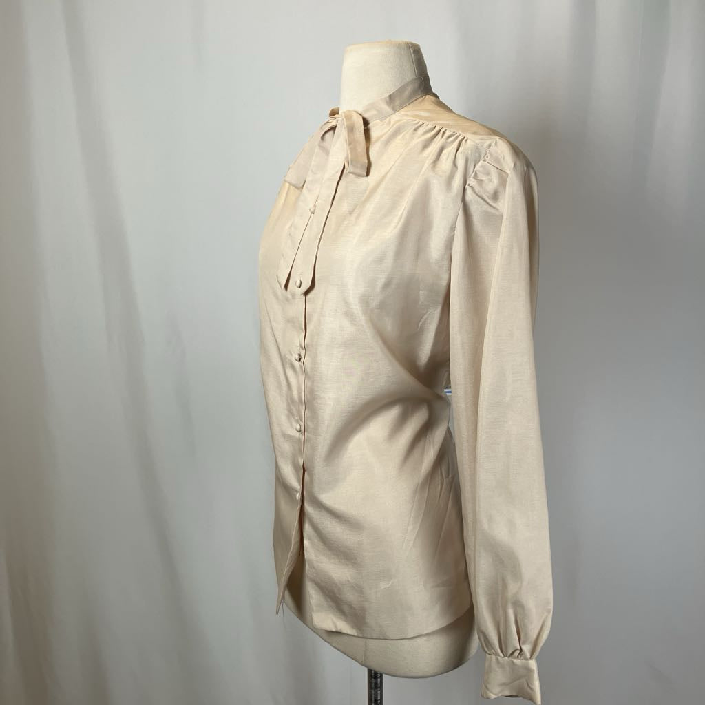 Beige blouse on a mannequin against a plain background