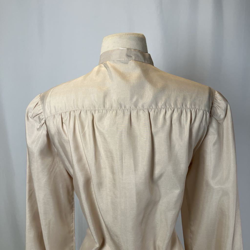 Beige blouse on a mannequin against a plain background