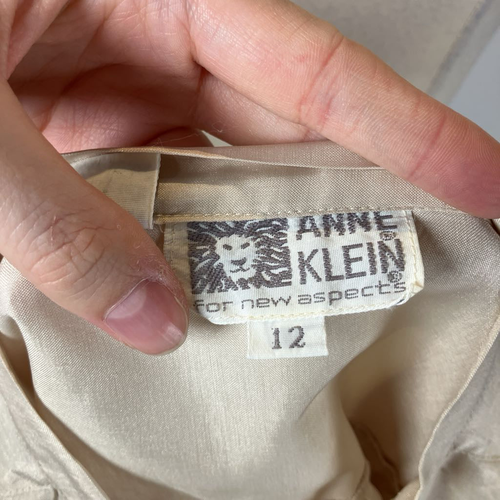 Close-up of a fabric label with 'Anne Klein' branding on beige material.