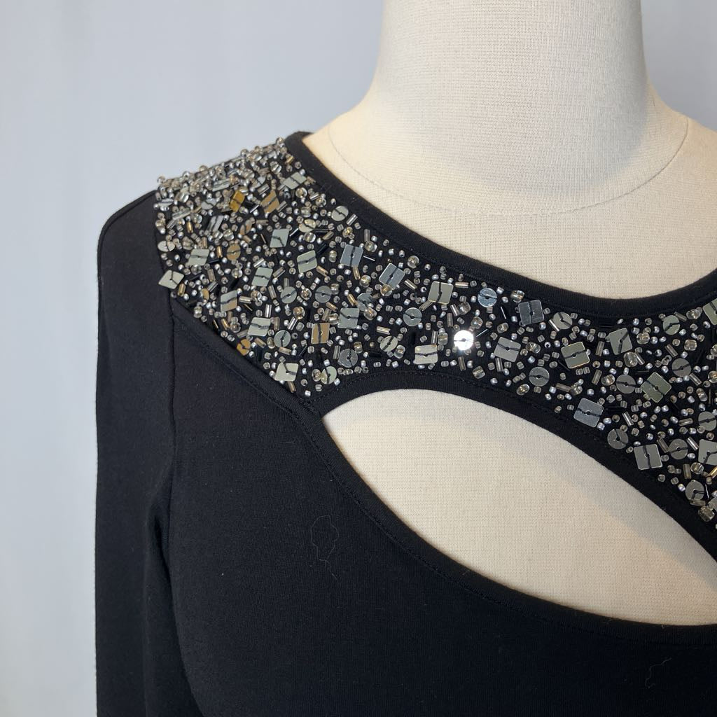 Black top with beading and a cutout on the chest against a white background. 