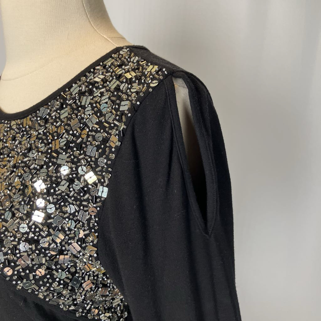 Black top with beading and a cutout on the chest against a white background. 