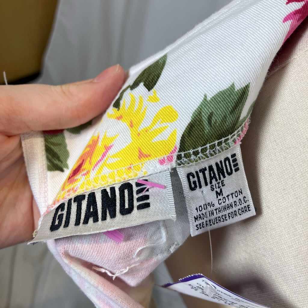 Close-up of a floral fabric with 'GITANO' label held by a hand.
