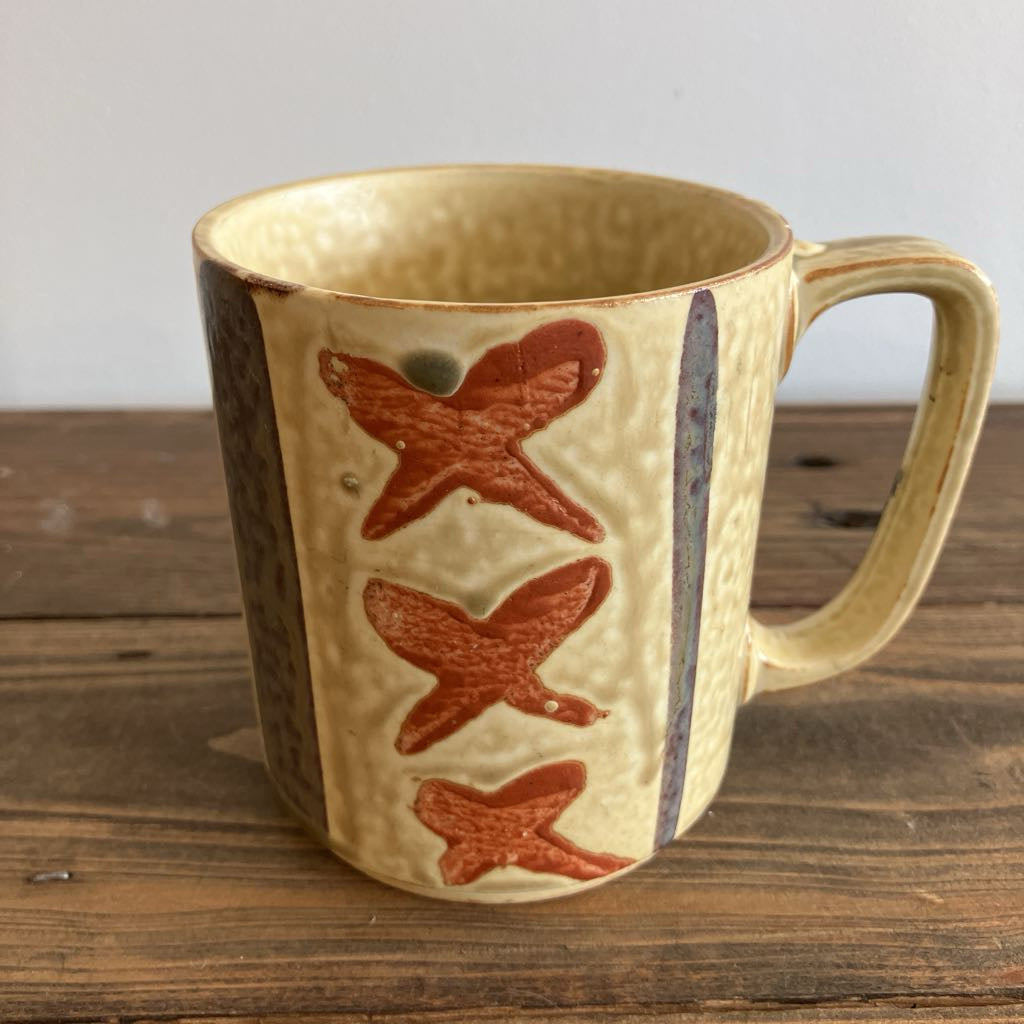 Ceramic mug with an "x" design on a wooden surface