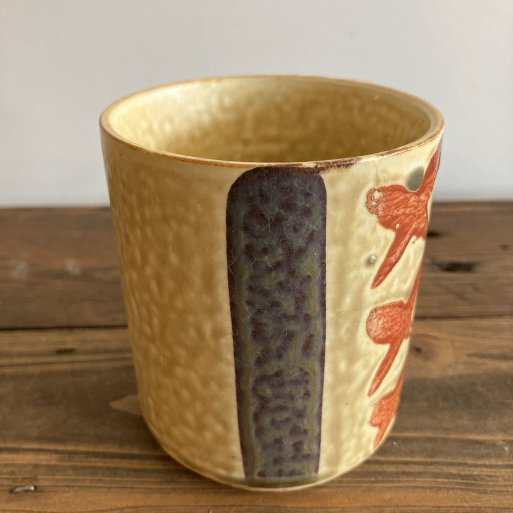 Ceramic cup with textured surface and floral design on a wooden surface