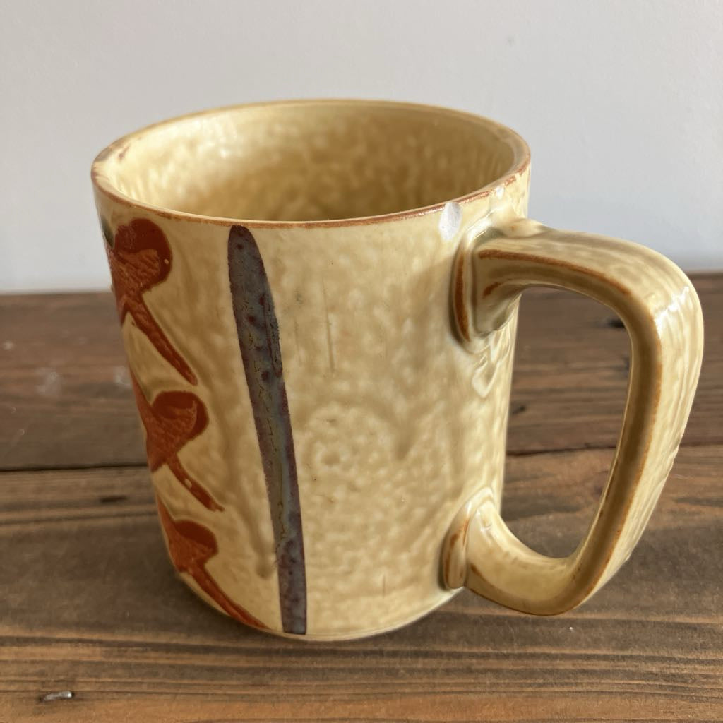 Beige ceramic mug with decorative patterns on a wooden surface