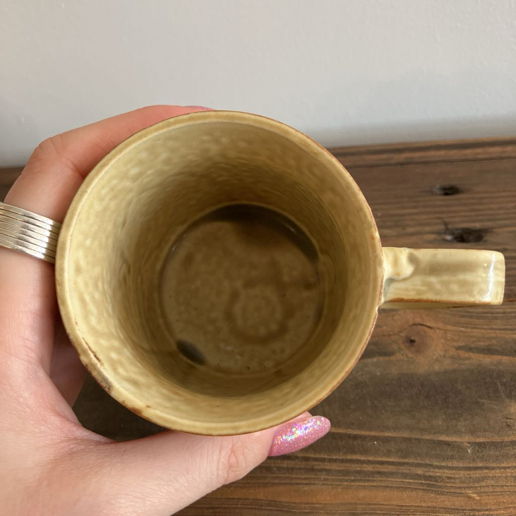 Hand holding a ceramic mug with a floral design on a wooden surface