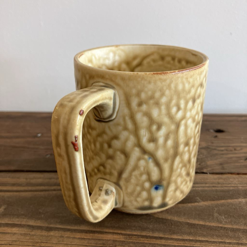 Textured ceramic mug on a wooden surface with a white background