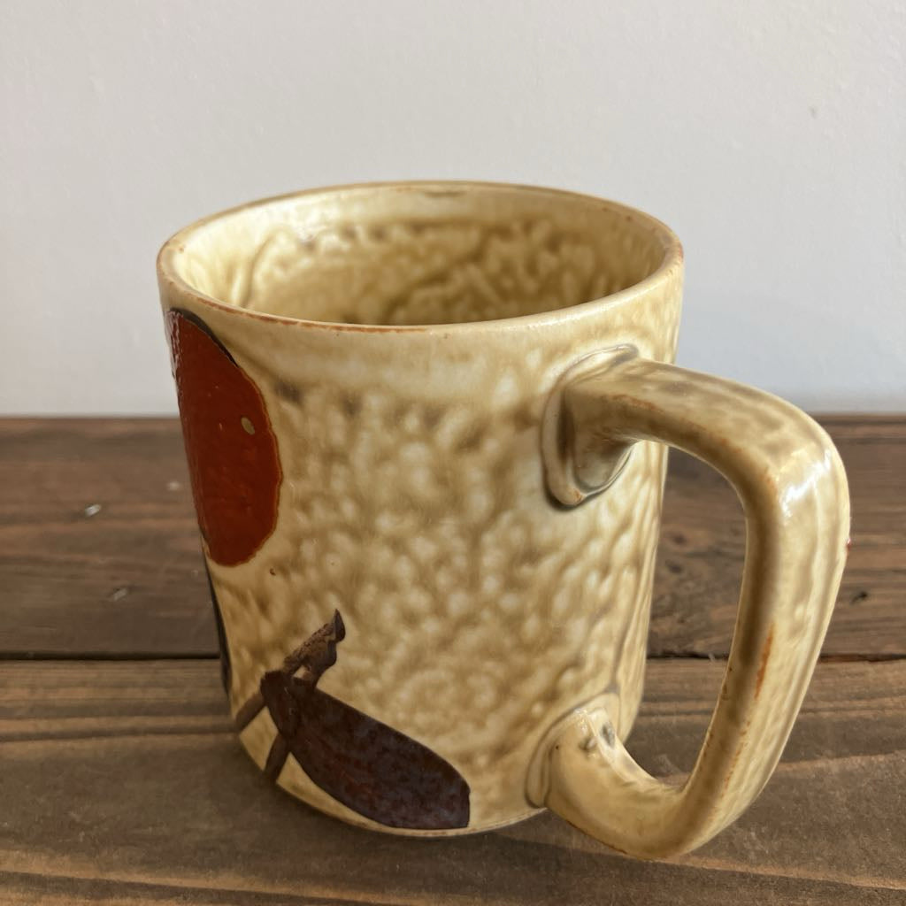 Beige ceramic mug with brown abstract design on a wooden surface