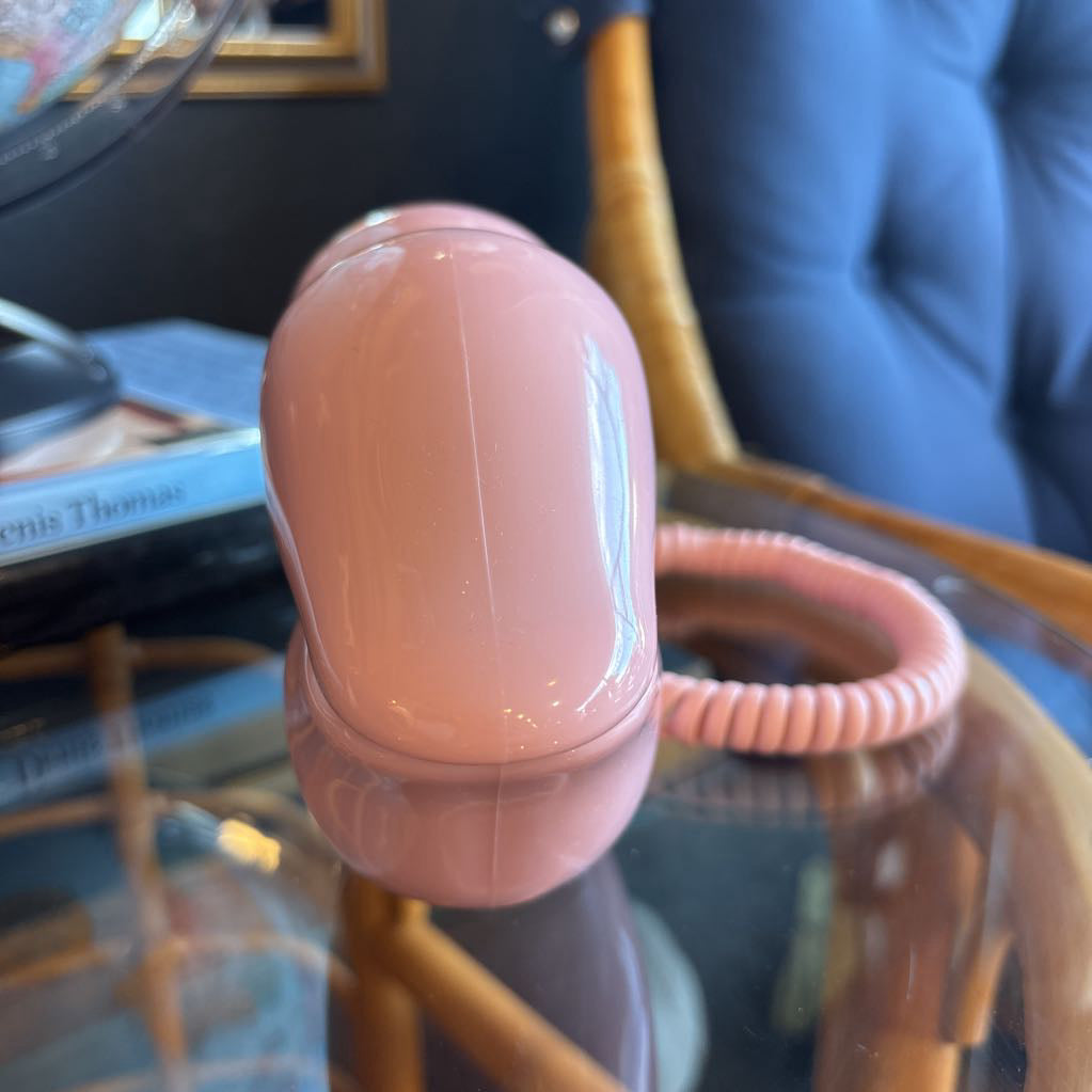 A corded phone of pink lips on a glass table in a room setting.