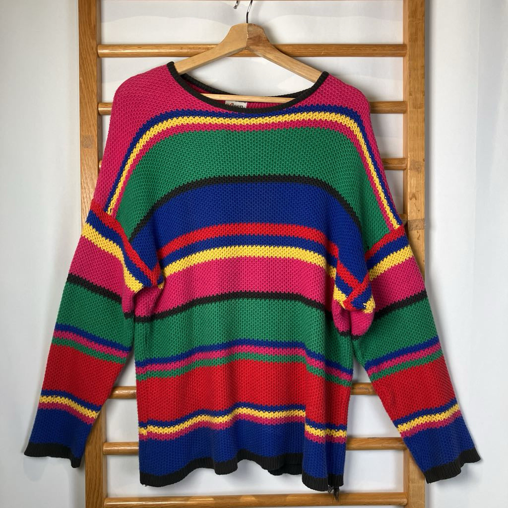 Colorful striped sweater hanging on a wooden rack against a white wall