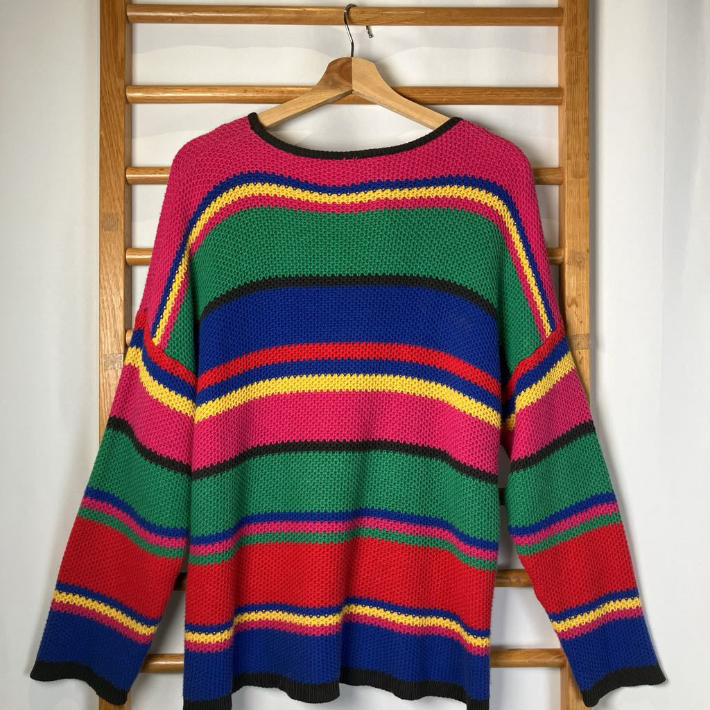 Colorful striped sweater on a wooden hanger against a white wall