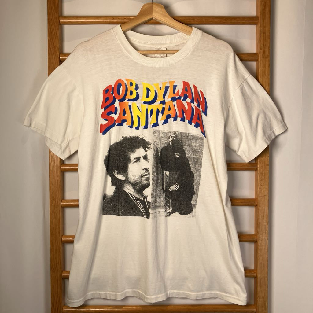 White t-shirt with Bob Dylan and Santana graphic on a wooden rack