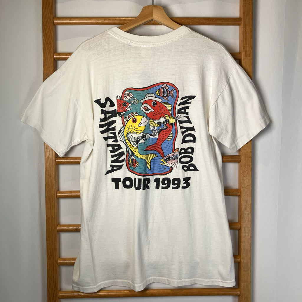 White t-shirt with colorful graphic design and text on a wooden rack