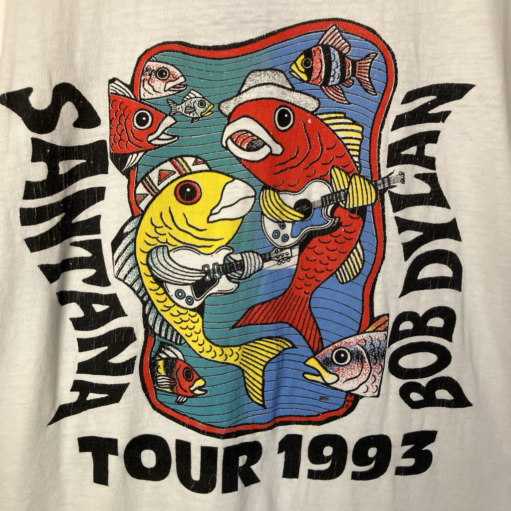 T-shirt design featuring colorful fish with instruments and text 'Santana Tour 1993 Bob Dylan' on a white background.