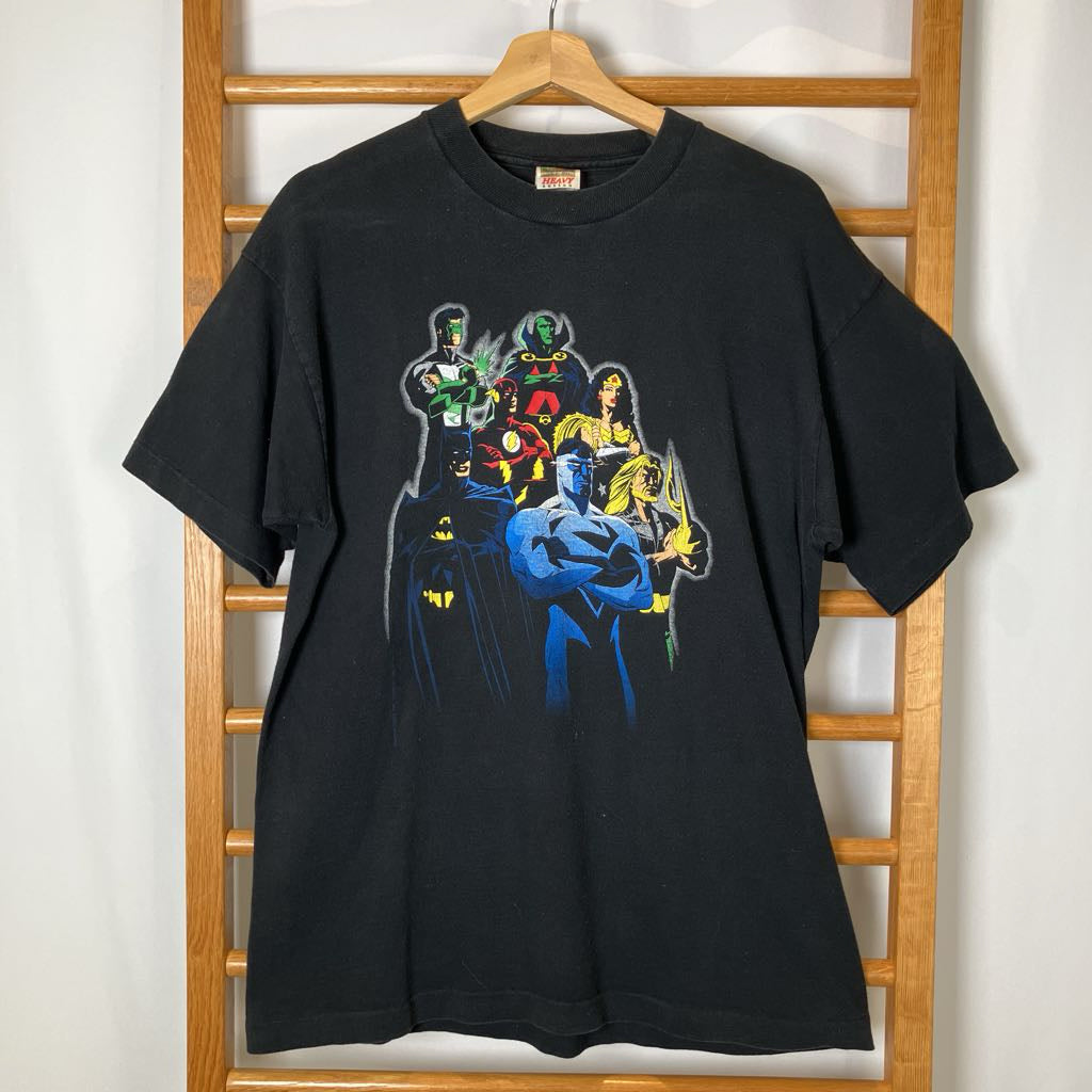 Black t-shirt with superhero graphic on a wooden hanger against a white wall