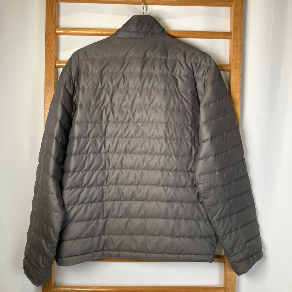 Gray puffer jacket hanging on a wooden rack against a white wall