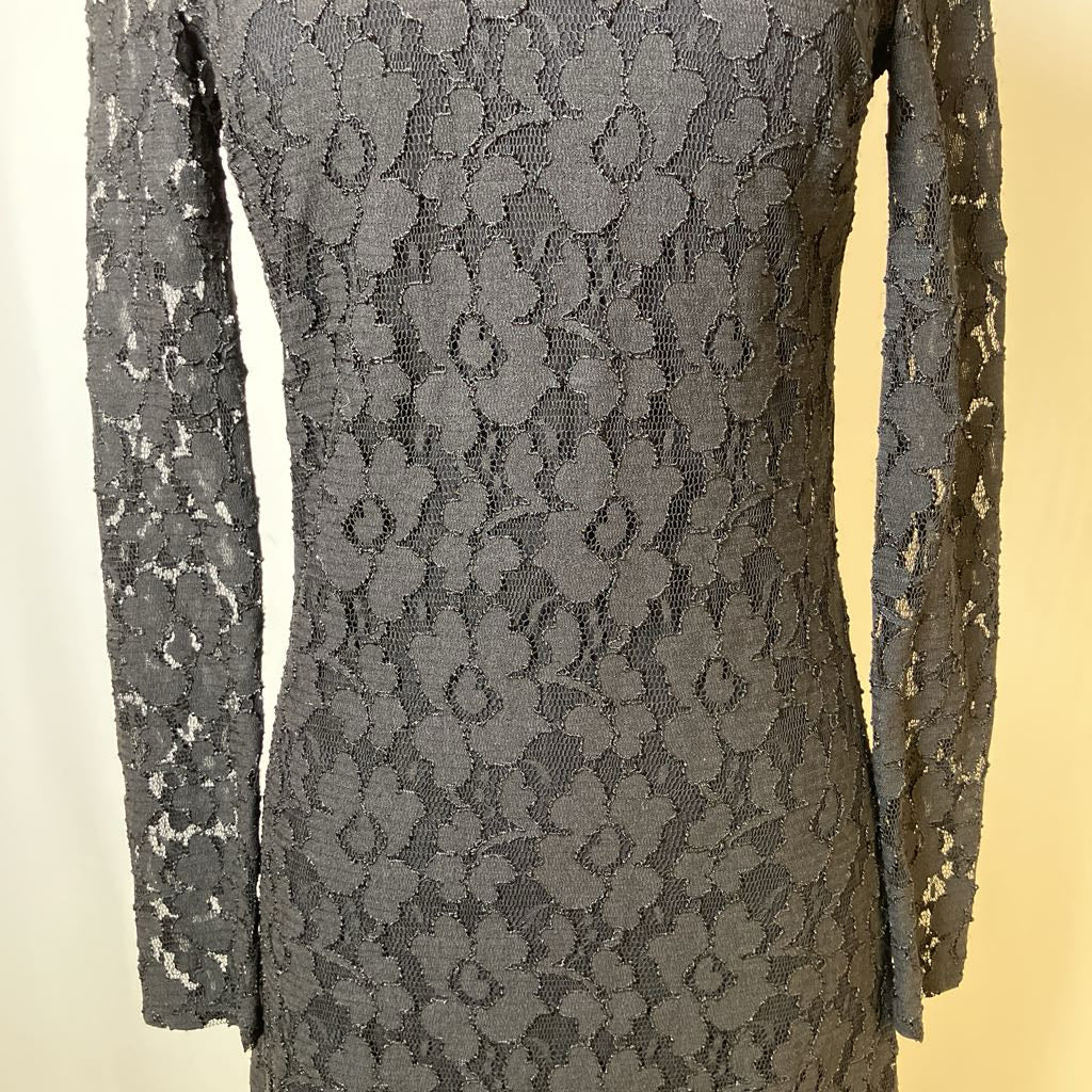 Close-up of a black lace dress with long sleeves on a beige background