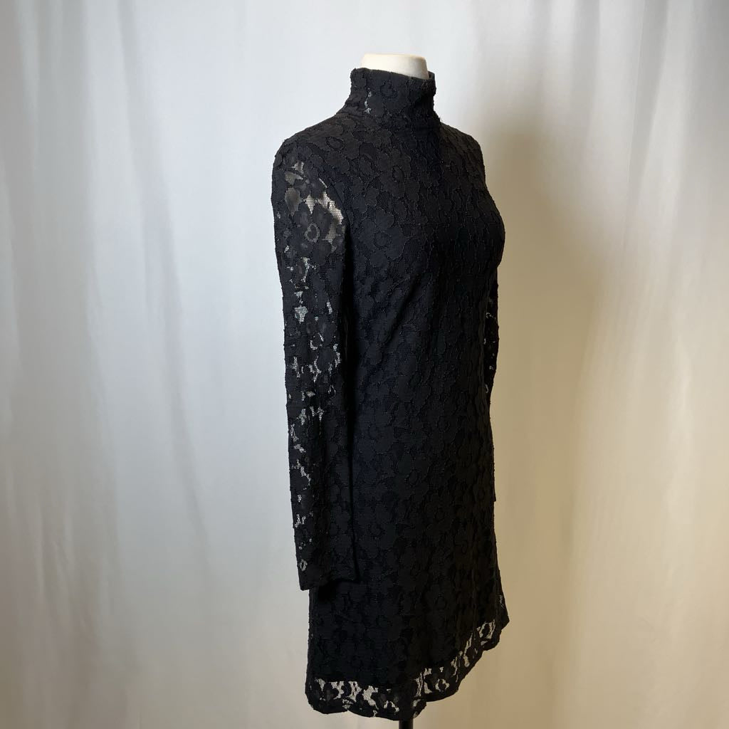 Black lace dress on a mannequin against a plain background