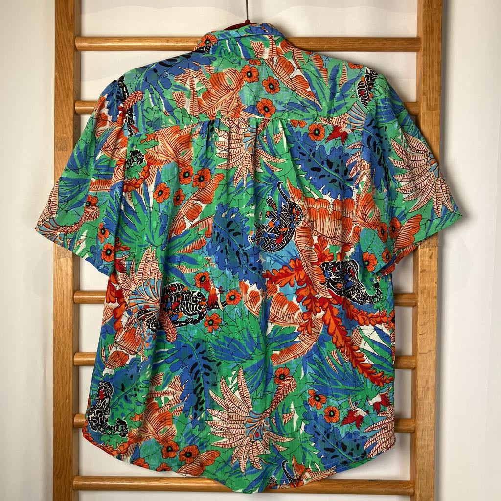 Colorful tropical shirt with floral pattern on a wooden rack.