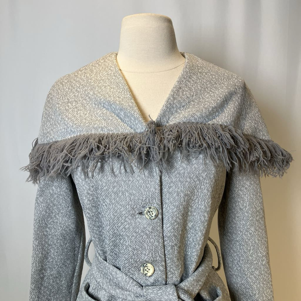 Gray textured coat with frayed trim on a mannequin against a neutral background