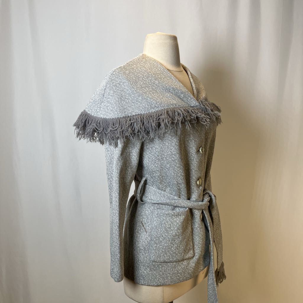 Gray textured coat with frayed trim on a mannequin against a plain background