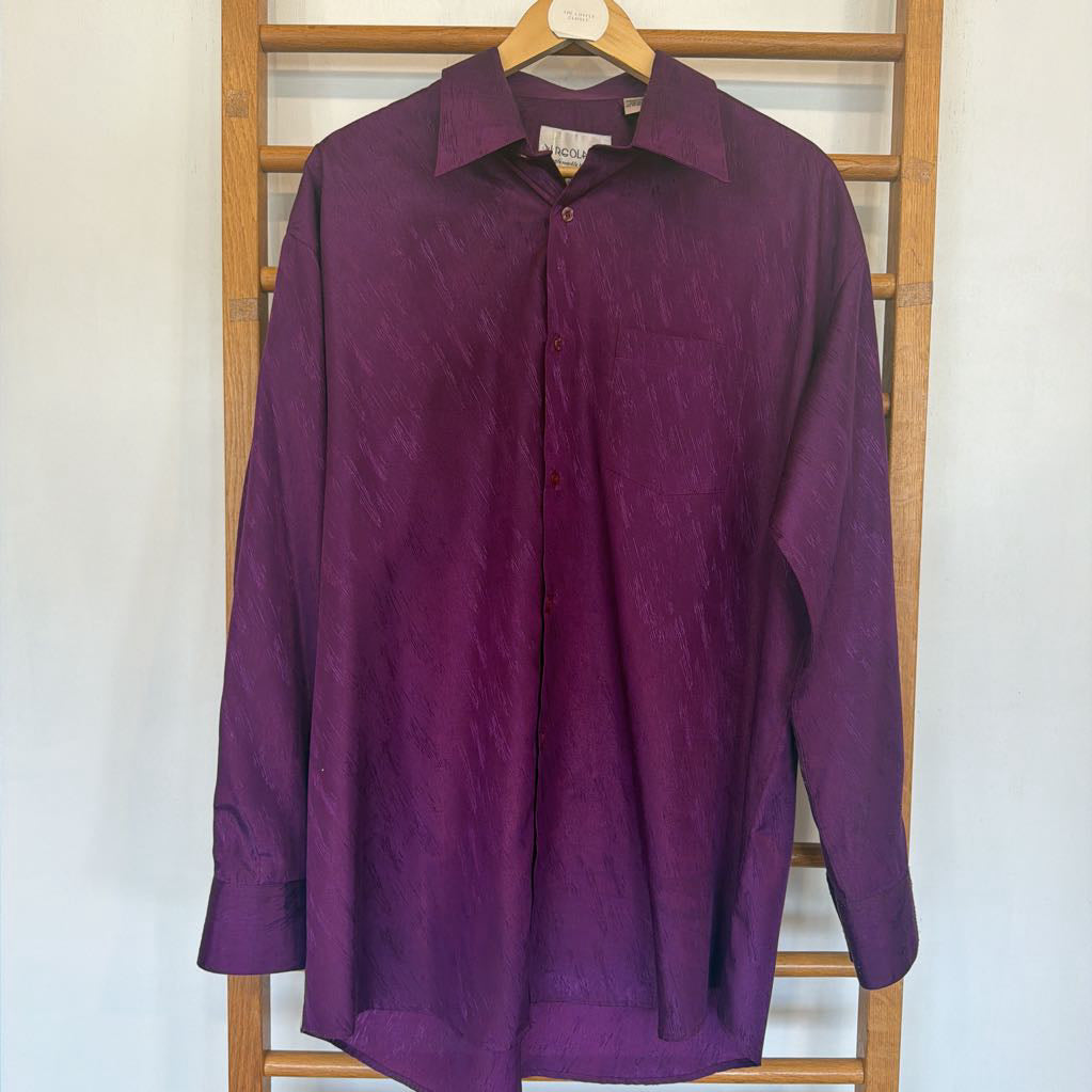 Purple shirt on a hanger against a white wall