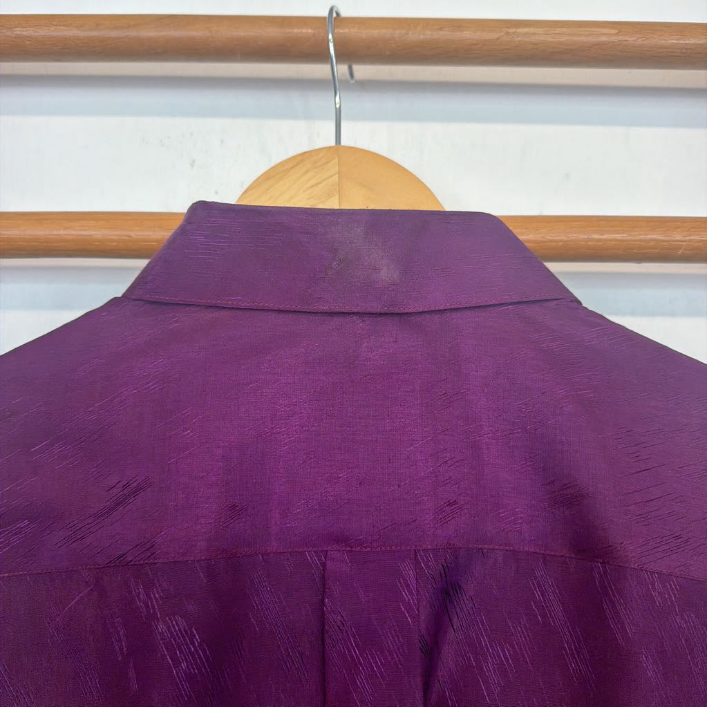 Purple shirt on a wooden hanger against a white wall