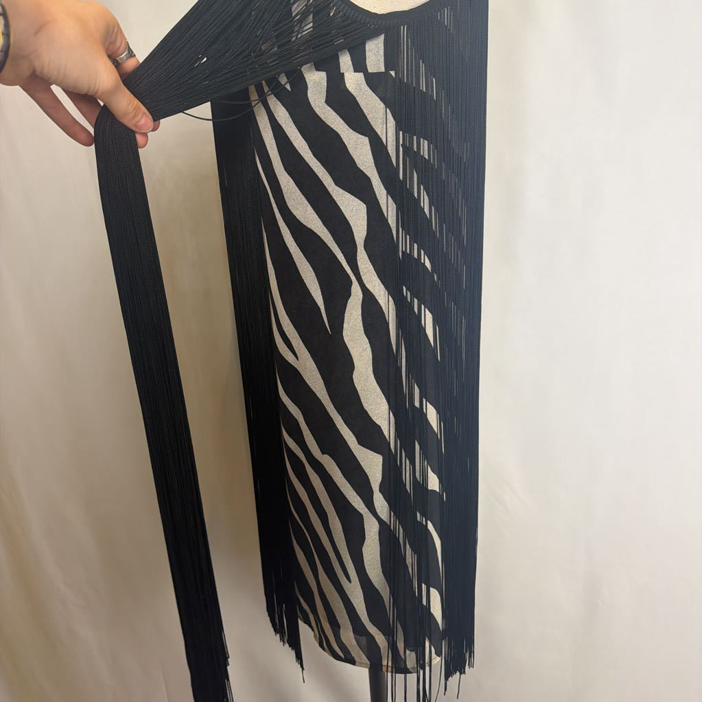 Zebra print dress with black fringe on a mannequin in front of a white wall. 