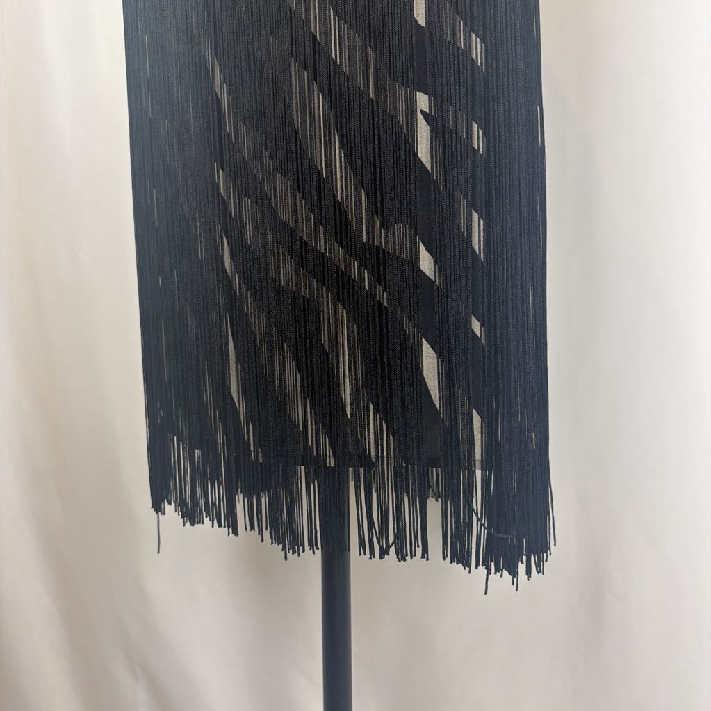 Zebra print dress with black fringe on a mannequin in front of a white wall. 