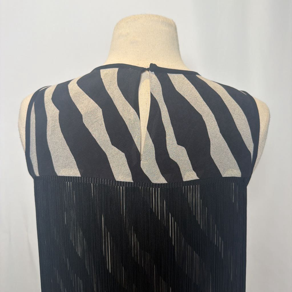 Zebra print dress with black fringe on a mannequin in front of a white wall. 